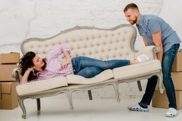 man-moving-sofa-with-lying-woman_23-2147758718